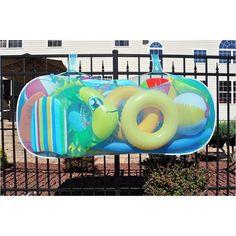 an inflatable pool float is sitting on the ground next to a black fence