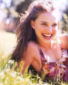 a young woman sitting in the grass smiling