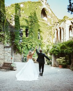 a bride and groom walking in front of an old building with ivy growing on it