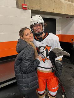 two people standing next to each other wearing hockey gear