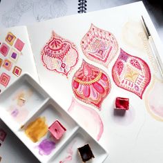 an artist's work is being displayed on a table with watercolors and ink