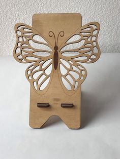 a wooden cutout of a butterfly on a white surface with two clips in it's wings