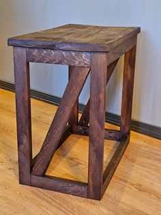 a small wooden table sitting on top of a hard wood floor next to a wall