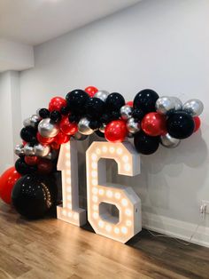 the balloon arch is decorated with black, red and silver balloons that spell out the number sixteen