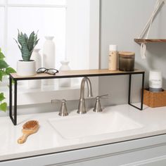 a bathroom sink sitting under a window next to a wooden brush and soap dispenser