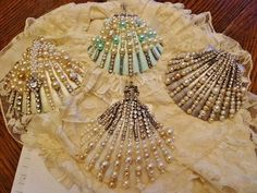 three seashells are sitting on a lace doily with pearls and glass beads