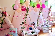 a room filled with lots of pink and green balloons hanging from the ceiling next to furniture