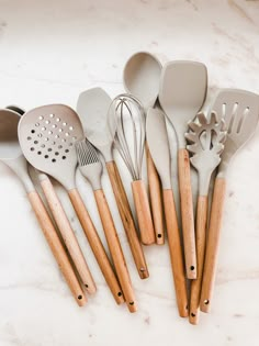 the kitchen utensils are lined up on the counter top with wooden spoons and spatulas