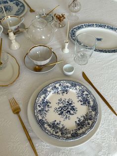 the table is set with blue and white plates, silverware, and gold utensils