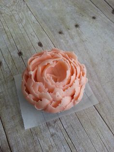 a cupcake with pink frosting sitting on top of a piece of wax paper