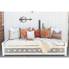 a white daybed with lots of pillows sitting on it's sides next to a brick wall