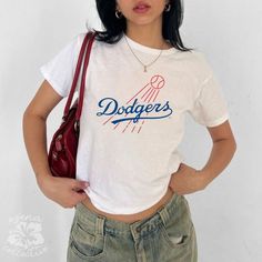 Vintage LA Dodgers Retro Baby Tee  💕 ABOUT - The same baby-tee fit you know & love! - Super comfortable and soft material. - 100% sustainably sourced ring-spun cotton, coloured with OEKO-TEX certified low-impact dyes. - All t-shirts come with pearlized, tear-away labels for total comfort and a scratch-free experience. 🌟SIZING - Please find the size chart in the description before purchasing. 💖CARE/ WASH - Machine wash: warm 30C (max 40C or 105F) - Non-chlorine bleach as needed - Tumble dry: l Retro Crew Neck Tops With Name Print, Retro College Tops With Logo Print, Retro Tops With Logo Print For College, Summer College Tops With Logo Print, Retro White Tops With Letter Print, Fan Apparel Slogan Crew Neck Top, Slogan Crew Neck Top For Fans, Retro White Slogan Tops, Cotton Slogan Top For Fan Apparel