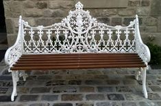 a white bench sitting in front of a brick wall