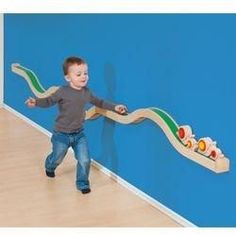 a young boy is playing with a toy snake on the wall next to a blue wall