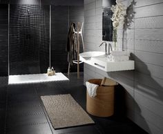 a modern bathroom with black tile and white fixtures, including a walk - in shower