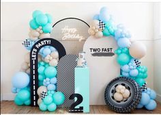 balloon arch with two fast signs and balloons on the floor in front of it, next to a tire