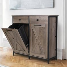 a wooden cabinet with two doors and a trash can in it