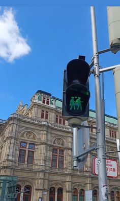 a traffic light on a pole in front of a building with a green pedestrian crossing sign