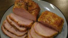 a white plate topped with sliced meat on top of a wooden table