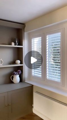 an empty room with shelves and vases on the windowsill, next to a radiator