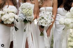 a group of bridesmaids in white dresses holding bouquets