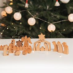 wooden nativity figures next to a christmas tree