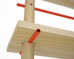 an orange pipe is attached to the side of a wooden structure with two red poles