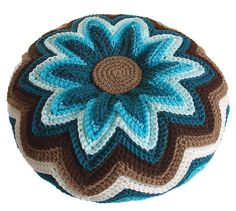 a crocheted blue and brown flower on top of a pillow