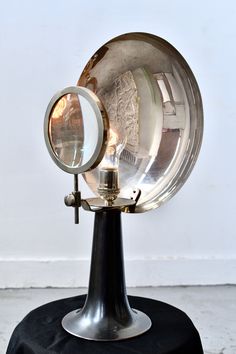 an old fashioned magnifying glass sitting on top of a black table with a white wall in the background