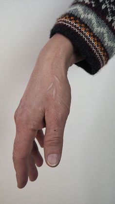 a person's hand with an arrow tattoo on the left side of their arm