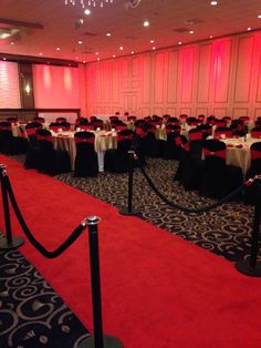 a banquet room set up with red and black tablecloths, white tables and chairs