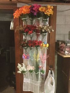 flowers are arranged in clear vases on a wooden shelf next to a white bag