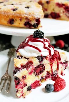 a slice of berry cheesecake on a white plate with raspberries and blueberries