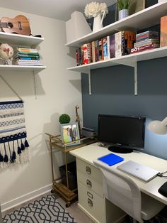 a desk with a computer on top of it in front of a bookshelf