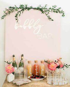 a table topped with bottles and vases filled with flowers next to a sign that says hello baby