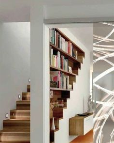 an open door leading to a white room with bookshelves and wooden flooring