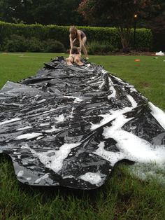 a man is working on a large piece of black tarp in the middle of a field