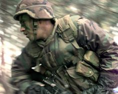 a man in camouflage running through the woods