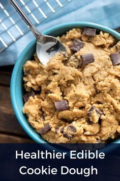 a blue bowl filled with cookie dough and chocolate chips on top of a wooden table