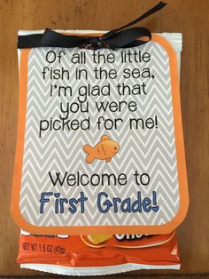 an orange and white sign with a black bow on it that says, of all the little fish in the sea i'm glad that you were picked for me welcome to first grade