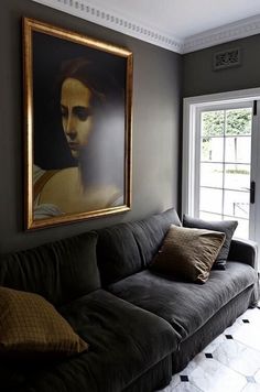 a living room filled with furniture and a painting hanging on the wall above it's doorway