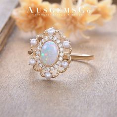 an opal and diamond ring sits on a table next to some flowers with the words ausgemsgo written above it