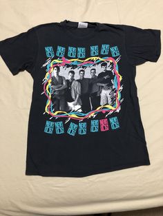 a t - shirt with an image of three men on it sitting on top of a bed