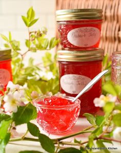 three jars filled with jam sitting on top of a table next to flowers and plants