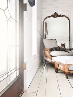 a cat laying on top of a bed next to a mirror in a room with white walls