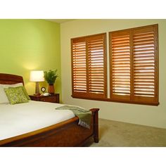 a bedroom with green walls and wooden shutters on the windows, along with a bed