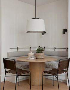 a table with two chairs around it and a lamp hanging from the ceiling over it