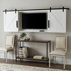 two chairs and a table in front of a flat screen tv mounted on a wall