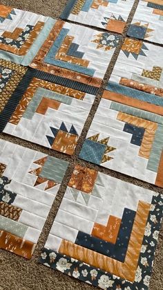 four quilts laid out on the floor with different colors and patterns, all arranged in squares