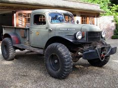 an old pick up truck parked in front of a building with large tires on it